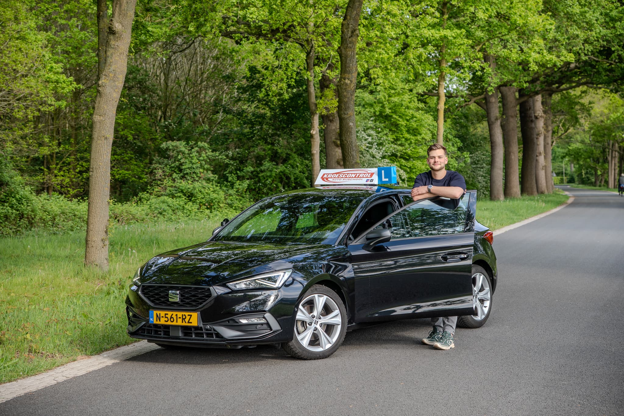 Jason Kroes met de Kroescontrol lesauto op een laan in Zwolle